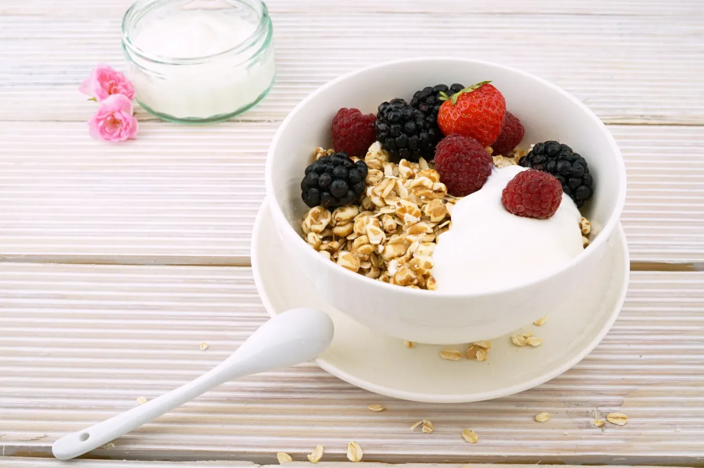 Skål med frokostblanding, yoghurt og friske bær på et lyst trebord